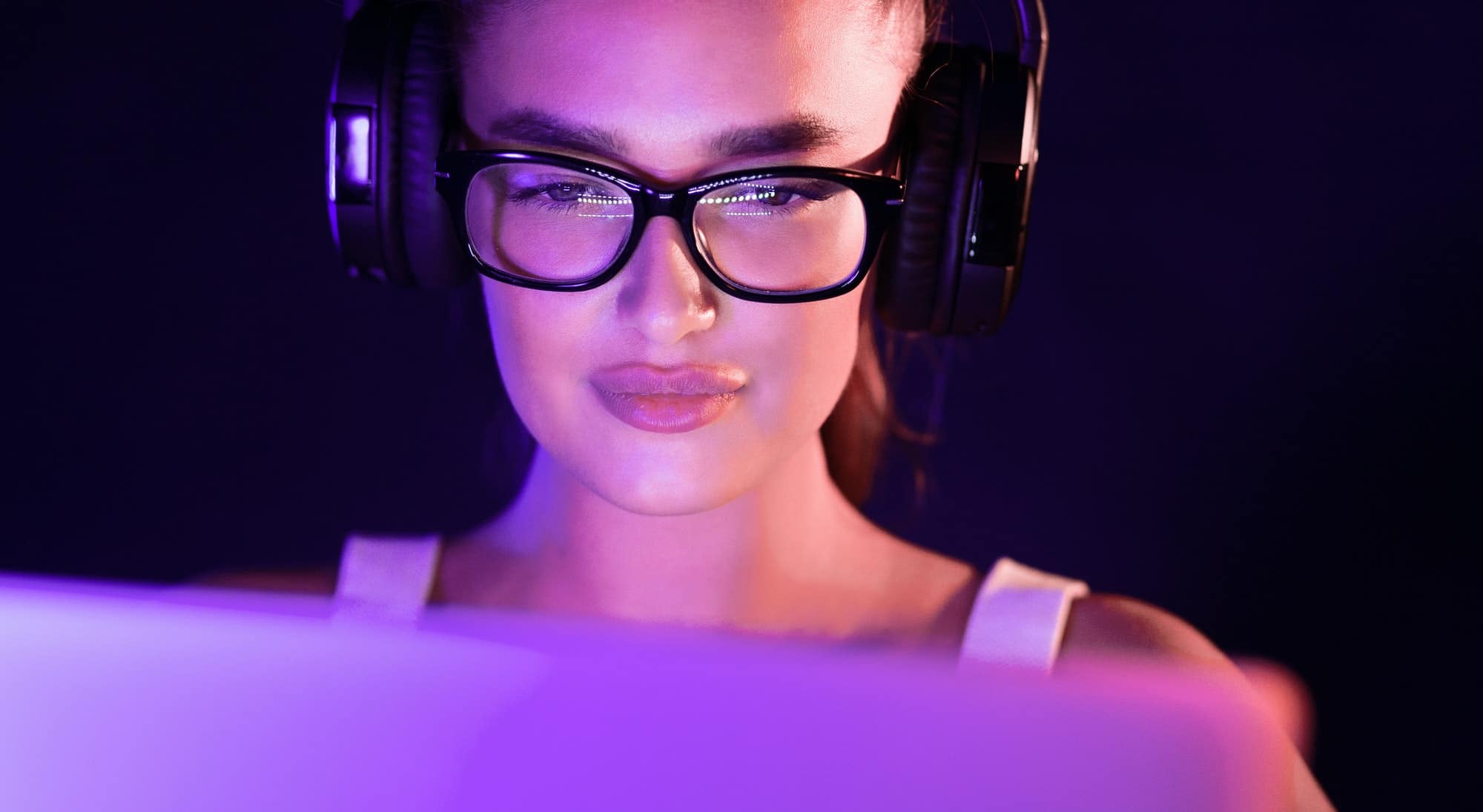 Student watching online tutorials, wearing headphones in the night