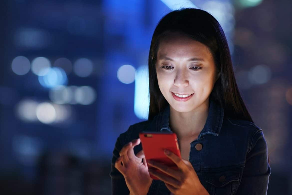 Woman work on smart phone over business district at night