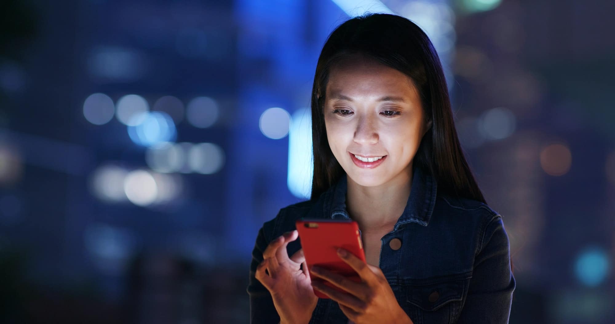 Woman work on smart phone over business district at night